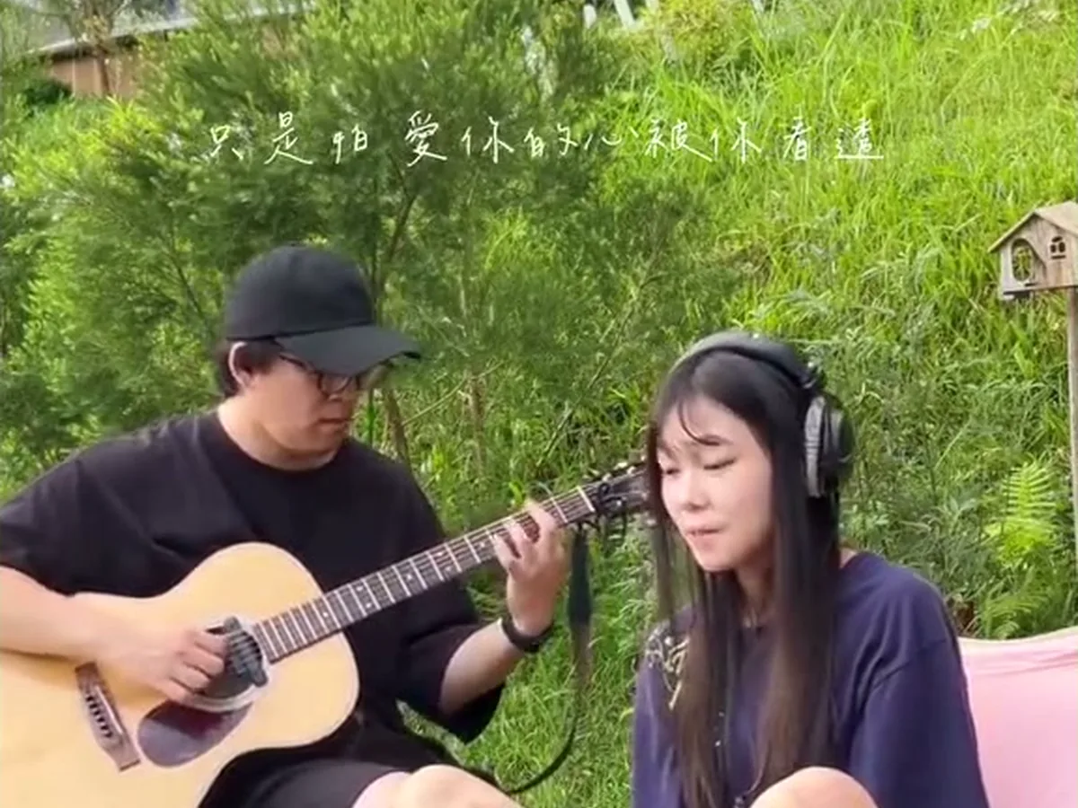 情侶在白色圓頂旁的草地彈吉他唱歌