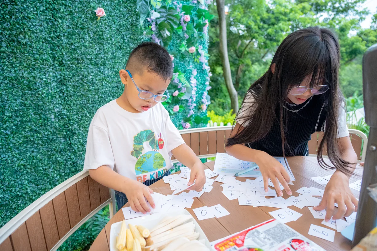 孩子在戶外圓桌使用字卡進行英文拼字遊戲